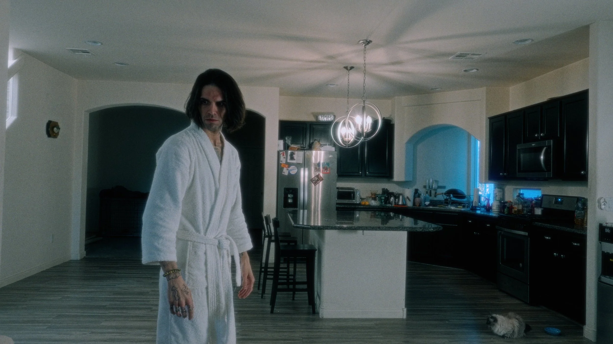 A man in a white robe standing in a kitchen